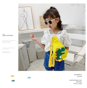 Detail showing cartoon dinosaur crossbody bag worn by child model in yellow canvas