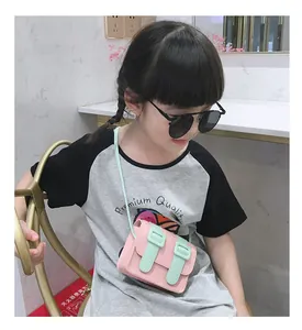 Kids mini crossbody bag in pink and mint green silicone shown on a child model