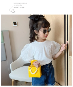 Kleinkind trägt weißes T-Shirt mit gepunkteten Puffärmeln und gelbe Perlenhandtasche