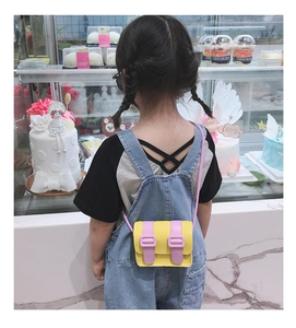 Rear view of a child wearing the yellow and pink mini satchel bag in a bakery setting