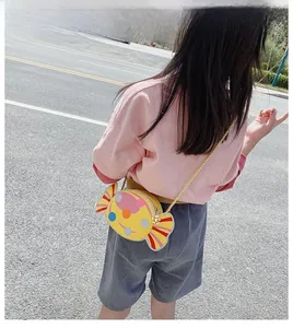 Detail of cute candy-shaped yellow crossbody bag with dots shown on a child model