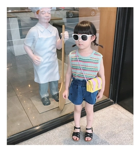 Kids fashion style with mint green knit vest, denim shorts and a colorful crossbody bag