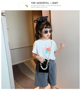 Detail eines weißen Grafik-T-Shirts und grauer Shorts mit Perlenhandtasche für Kinder