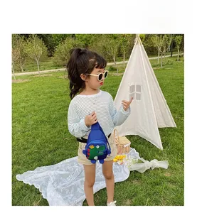 Little girl wearing a dark blue dinosaur chest bag outdoors with adjustable strap