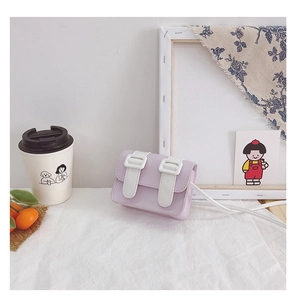 Detail shot of mini purple crossbody bag with white buckles on textured surface
