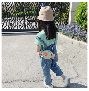 Outdoor shot of a toddler wearing a cute mint green candy-shaped crossbody bag