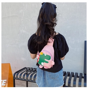 Detailed back view of a pink kids dinosaur chest bag worn by a young model outdoors
