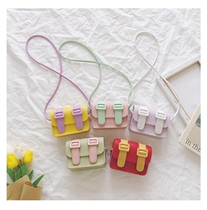 Flat lay of colorful macaron-toned mini crossbody bags for girls on white fabric