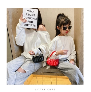 Détail de mini sacs plissés rouges et noirs avec chaînes dorées dans un décor cosy