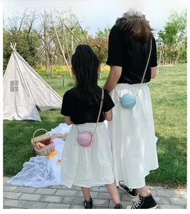 Pink and light blue basketball shaped crossbody bags with gold chains in outdoor park