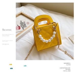 Details der gelben Lackleder-Kindertasche mit Steppmuster und edlem Perlengriff