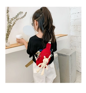 Detail of red canvas kids chest bag with a cute white long-eared rabbit doll accessory