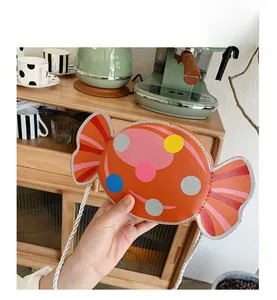 Detailed close-up of orange candy-shaped kids crossbody bag with colorful polka dots