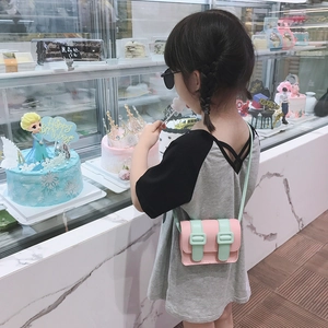Girl wearing a mini pink and mint green crossbody satchel bag for kids with strap