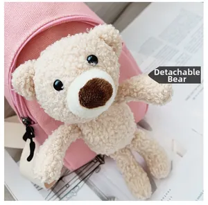 Detail view of pink canvas bag with detachable beige teddy bear plush pendant