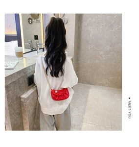 Détail du sac à bandoulière plissé rouge avec chaînes dorées et plastiques pour filles