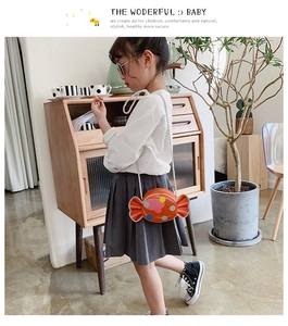 Girl wearing a cute orange candy shaped crossbody bag with colorful polka dots and rope strap