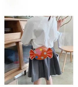 Detail view of a child wearing the orange candy-shaped crossbody bag with colorful dots