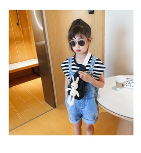 Detailed view of child wearing black crossbody bag with white plush bunny ornament