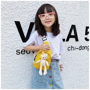 Detail of yellow canvas kids chest bag featuring a plush white bunny and adjustable strap