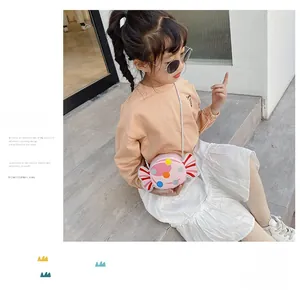 Pink candy-shaped kids crossbody bag with colorful polka dots shown on a young model