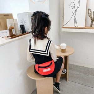 Sac banane en toile rouge pour enfant avec patch lettre porté en décor de café moderne