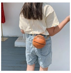 Outdoor view of child model wearing the basketball shaped mini crossbody bag with gold chain