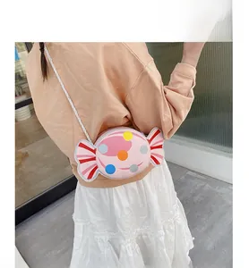 Pink candy-shaped kids crossbody bag with polka dots shown on back view during use