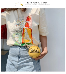 Detail view of yellow basketball-shaped crossbody bag with grain texture and gold chain
