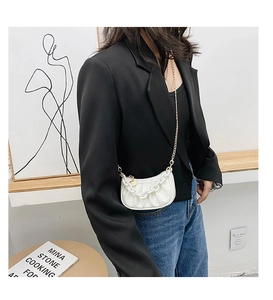 Détail du sac nuage plissé blanc avec chaîne acrylique et bandoulière dorée sur modèle