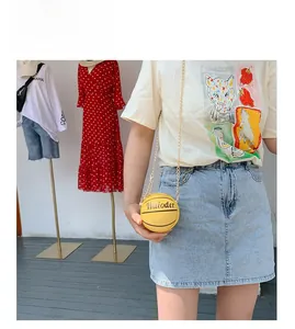 Detail of creative basketball-shaped crossbody bag with gold chain strap and yellow leather