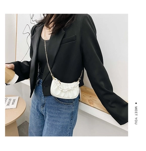 Vue détaillée d'un sac demi-lune plissé blanc avec de larges chaînes blanches et dorées