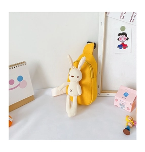 Detail of yellow canvas chest bag for kids featuring a cute plush bunny charm and zipper