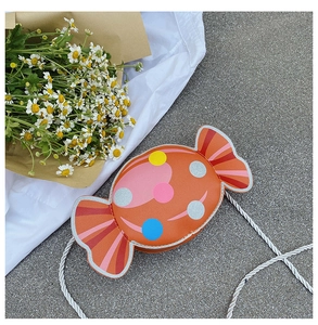 Close-up of orange candy shaped crossbody bag with colorful dots and braided rope strap