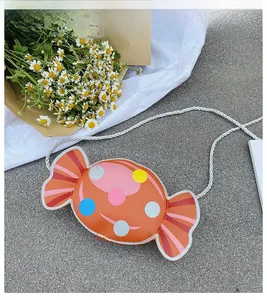 Detail shot of orange candy-shaped kids crossbody bag with colorful polka dots on fabric