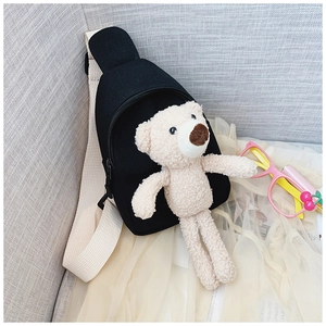 Close-up of black canvas kids crossbody bag with a cute plush bear and adjustable strap