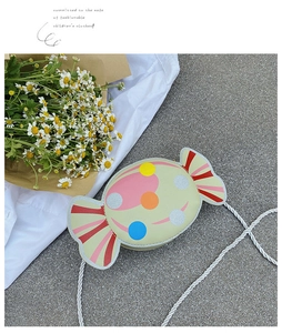 Detail of candy-shaped mint green kids crossbody bag with colorful polka dots and cord strap