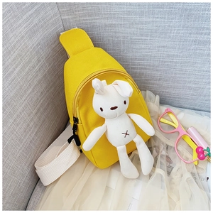 Detail of yellow canvas kids chest bag featuring a plush rabbit pendant and dual zippers