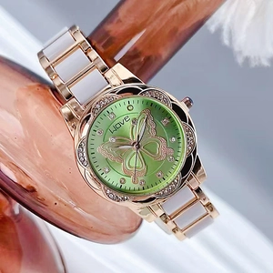 Détail d'une montre en or rose avec cadran papillon vert et lunette en strass