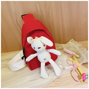 Detail view of a red canvas kids crossbody bag featuring a cute white rabbit doll charm