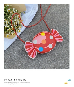 Macro view of red candy-shaped kids crossbody bag with colorful polka dots and woven strap