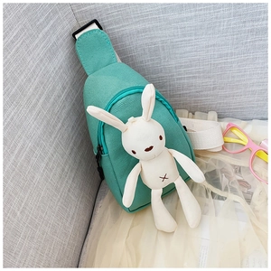 Detail of mint green canvas chest bag featuring a plush rabbit and adjustable strap