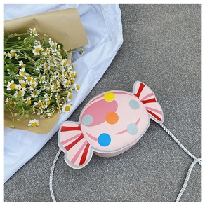Detail of pink candy-shaped crossbody bag with glitter dots and woven shoulder strap