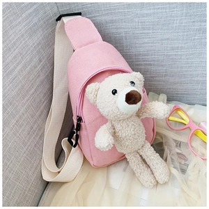 Detailed view of pink canvas crossbody bag with cute plush bear and cream shoulder strap