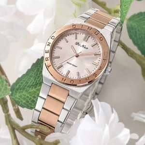 Gros plan d'une montre en acier argent et or rose avec cadran et fond floral doux