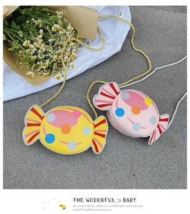 Detail of candy-shaped kids' crossbody bags in yellow and pink with colorful polka dots