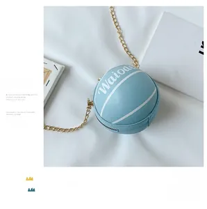 Detail of light blue basketball-shaped shoulder bag with gold chain on white fabric