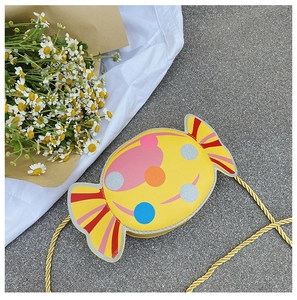 Close-up of yellow candy-shaped crossbody bag with colorful glitter polka dots