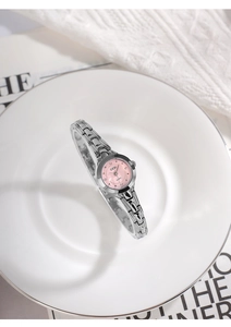 Gros plan détaillé d'une montre pour femme argentée avec cadran rose dans un plateau