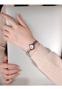 Détail de montre argentée pour femme avec cadran rose et bracelet chaîne sur poignet